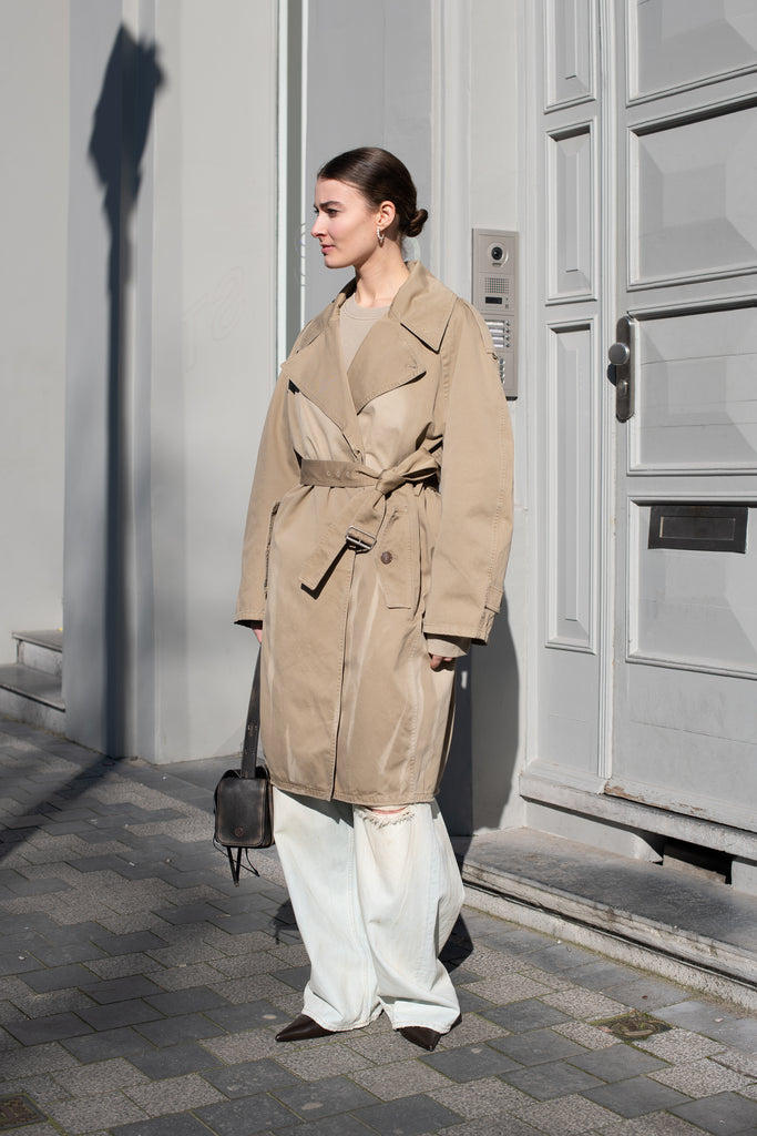 The Belted Trench Coat by Acne Studios is a cotton twill trench with a garment-dyed finish and an Acne Studios logo patch at the centre back