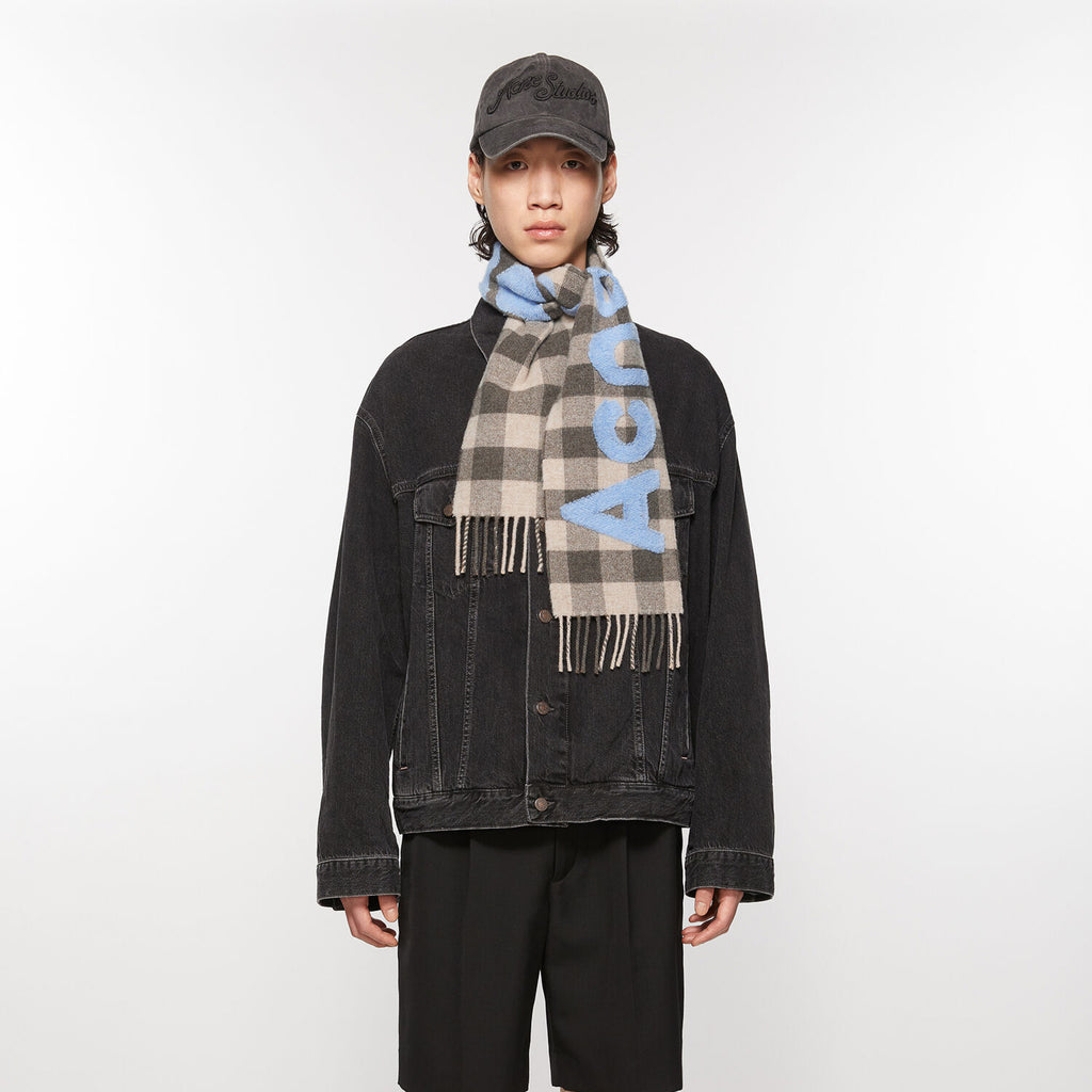 The Check Logo Scarf by Acne Studios features an all-over check pattern, contrast jacquard woven fil coupé Acne Studios logo, crafted from a rich wool blend