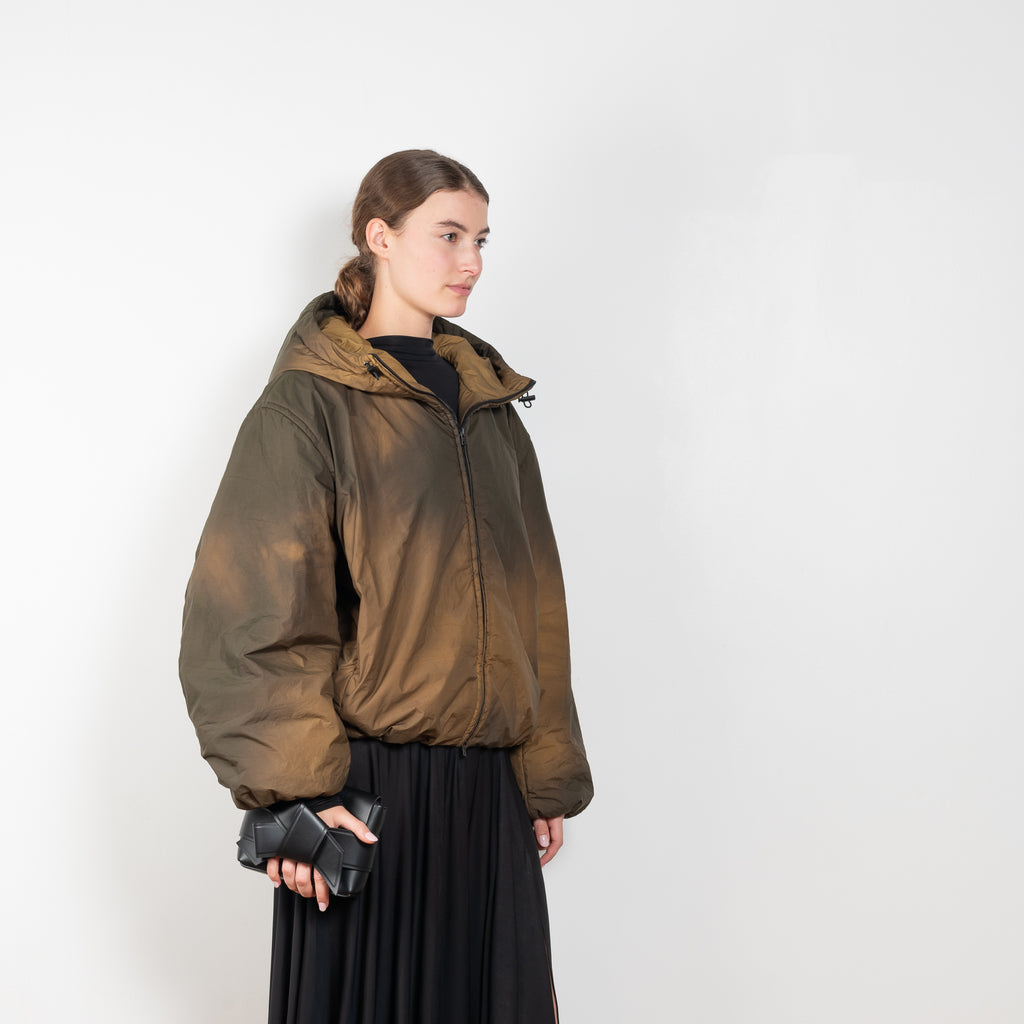 The Hooded Puffed Jacket by Acne Studios has a distinct coated finish crafted from water-repellant nylon