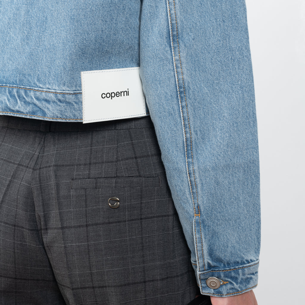 The Workwear Denim Jacket by Coperni is a cropped denim jacket with a zip closure and minimal details