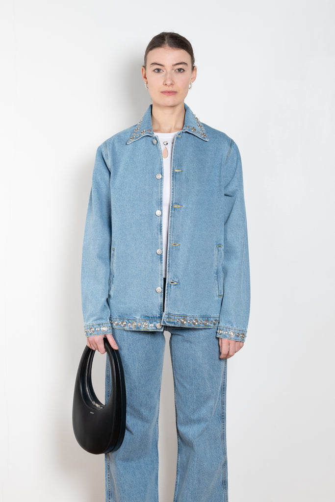 The Studded Denim Jacket by Coperni is a loose denim jacket with studded details and a front button closure