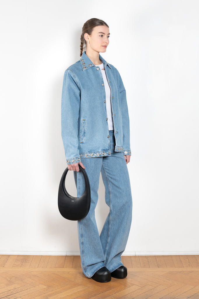 The Studded Denim Jacket by Coperni is a loose denim jacket with studded details and a front button closure