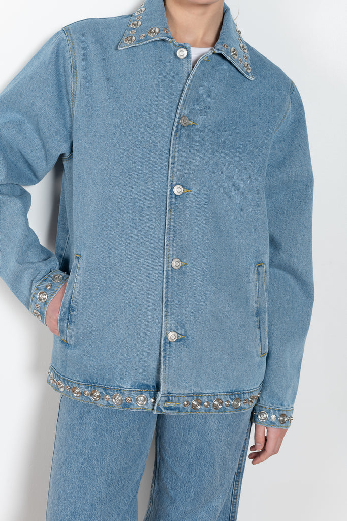 The Studded Denim Jacket by Coperni is a loose denim jacket with studded details and a front button closure