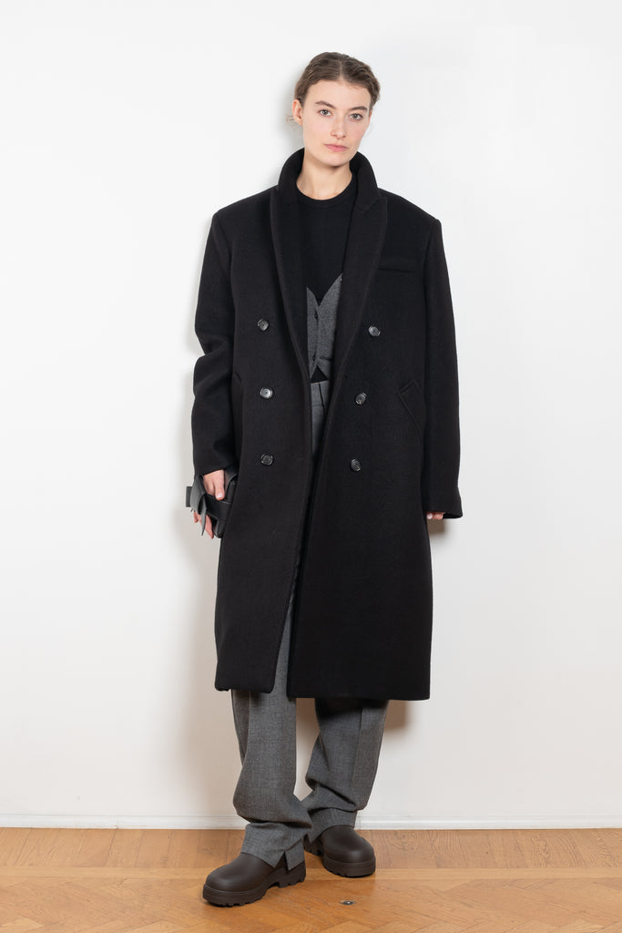 The Double Breasted Coat by KASSL Editions is a long coat crafted from boiled wool with classic men coat inspired detailing