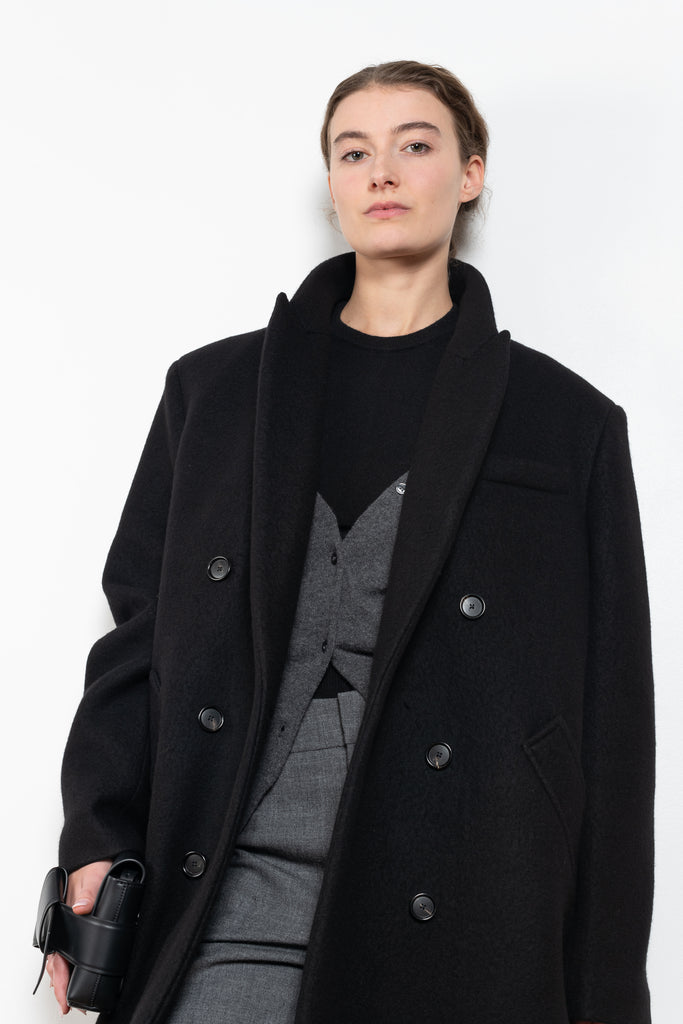 The Double Breasted Coat by KASSL Editions is a long coat crafted from boiled wool with classic men coat inspired detailing