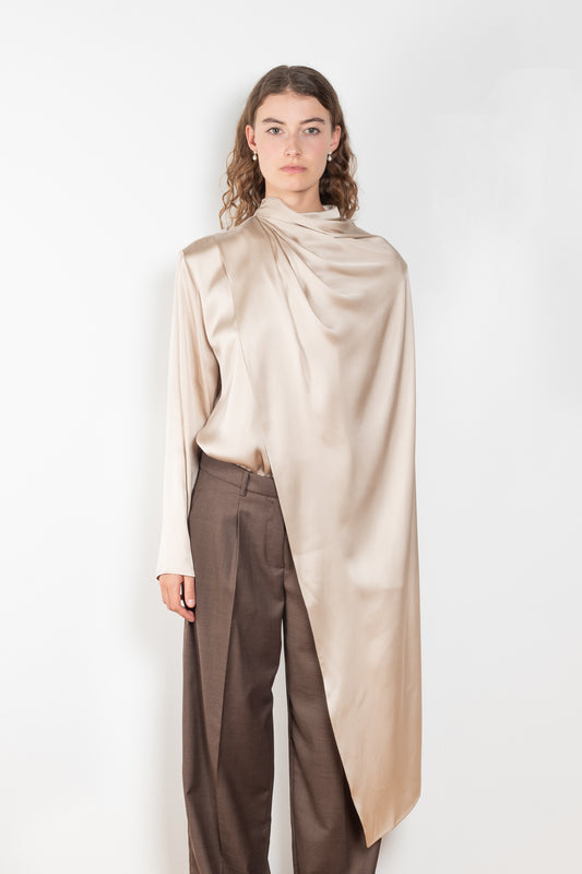 The Silk Shirt by Magda Butrym is a long-sleeve silk blouse with a round neck and carefully draped fabric that gives way to a dramatic cape that sweeps off the shoulder